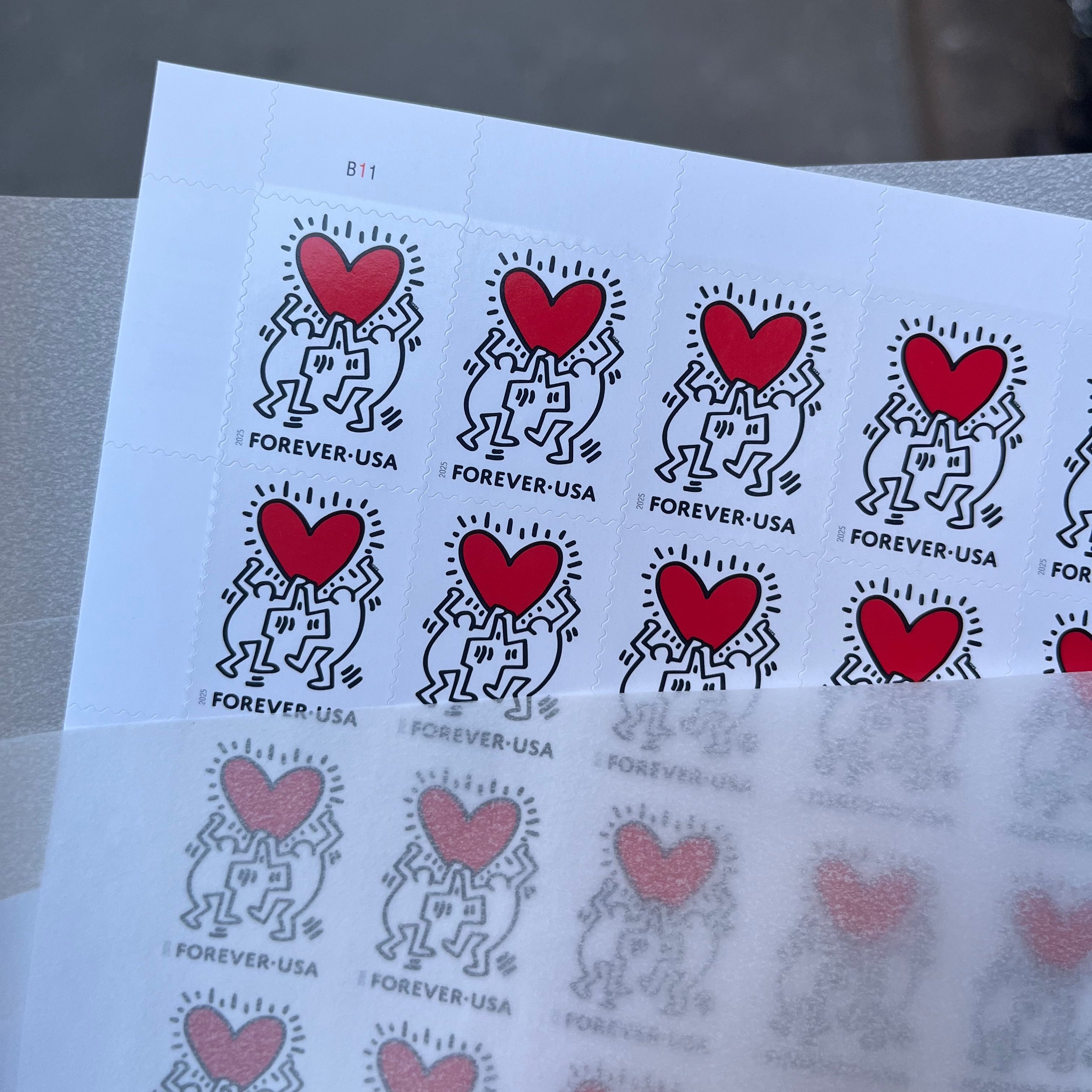 Sheet of postage stamps with red hearts and black designs on a white background.